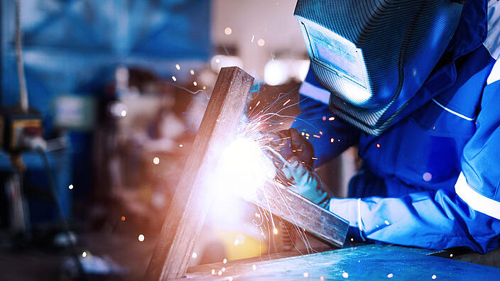 Professional welder in a factory welding steel bars
