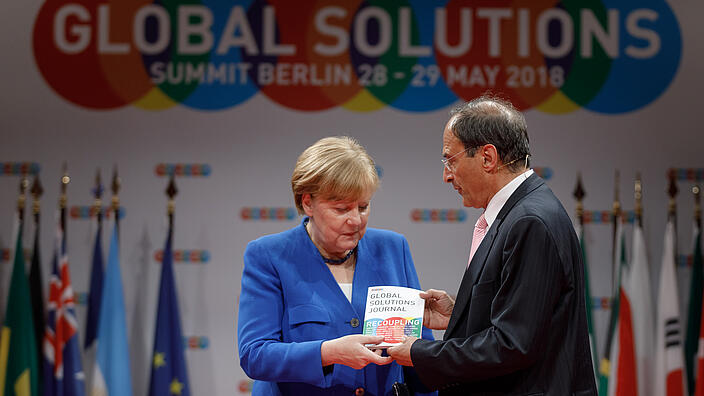 Angela Merkel is presented the Global Solutions Summit Journal by Dennis J. Snower